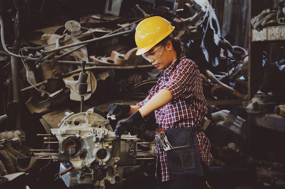 Woman engineer wearing safety gear, working on machine repair in an industrial setting