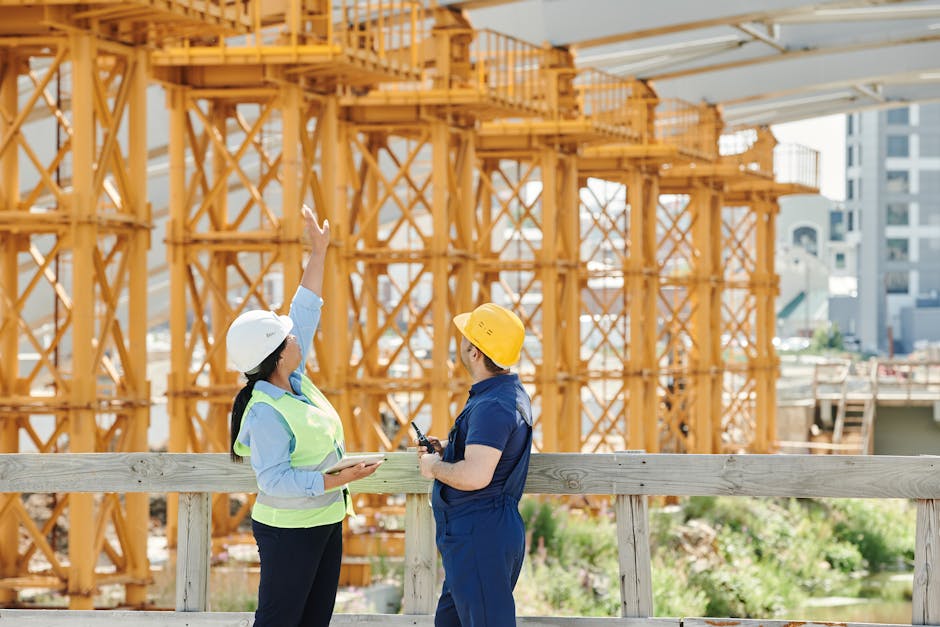 Two engineers in hardhats discuss projects at a busy construction site