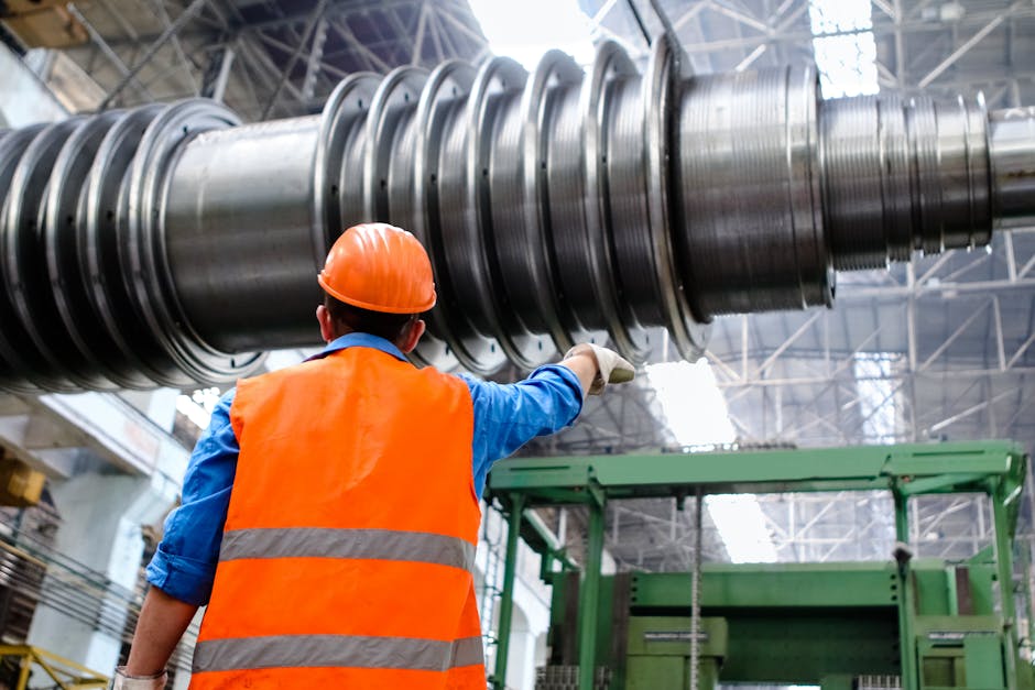 Engineer in high visibility vest and hard hat inspecting large machinery in factory setting