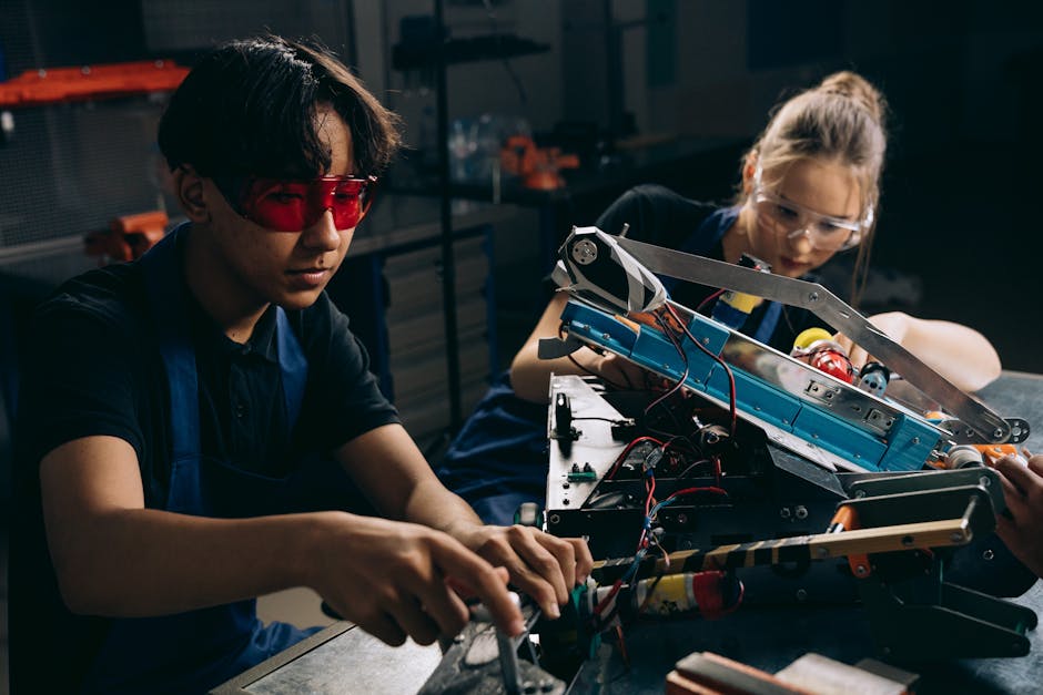 Two young engineers working on robotic equipment in a workshop setting